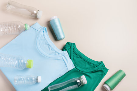 Plastic bottles and folded t-shirts, flat lay, concept of clothing production from recycled plastic materials, top view, copy spaceの写真素材