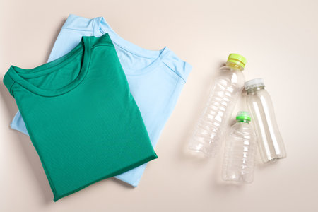 Plastic bottles and folded t-shirts, flat lay, concept of clothing production from recycled plastic materials, top viewの写真素材