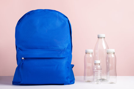 A blue backpack and plastic bottles, concept of recycled plastic used for sustainable fashion and...