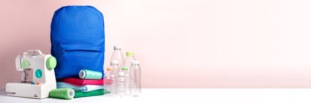 A blue backpack, t-shirts, sewing machine and plastic bottles, concept of sustainable fashionの写真素材