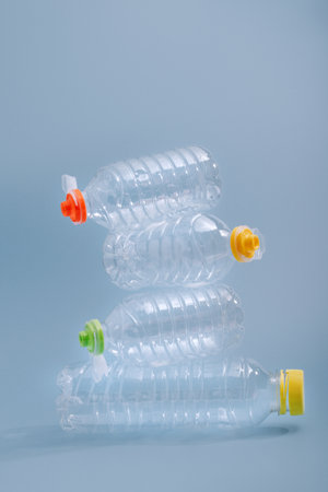 Stack of empty plastic bottles on a blue background, symbolizing plastic waste and environmental pollutionの写真素材