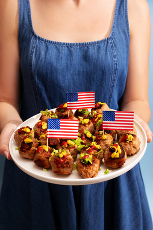 Woman holding plate of meatballs decorated with USA flags for 4th of July or other holidays.の写真素材