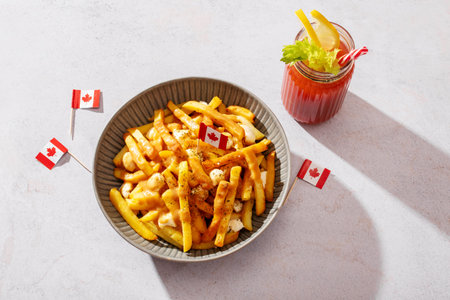 Canadian poutine with fries, cheese curds, and gravy in a bowl, decorated with Canadian flags, top...