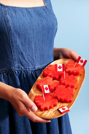 Woman in a denim dress holding tray with maple leaf shaped watermelonの写真素材