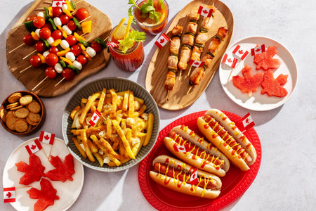 Top view of Canada Day party food with poutine, hot dogs, fruit, skewers, and donuts decorated with Canadian flagsの写真素材