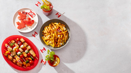 Border of Canada Day party food with poutine, hot dogs, decorated with Canadian flag, copy space