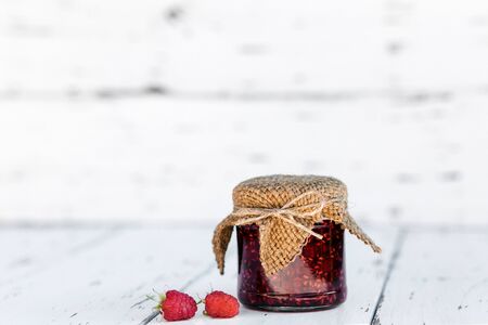 Raspberry jam in a jar on the wooden table on white backgrounの写真素材