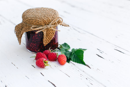Cooking jam. Raspberry jam in a jar on the wooden table