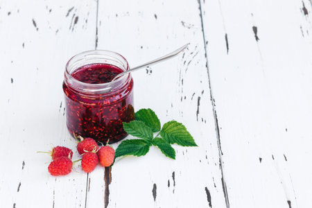 home-made Raspberry jam in a jar on the wooden table