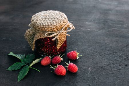 Cooking jam. Raspberry jam in a jar on the wooden tableの写真素材
