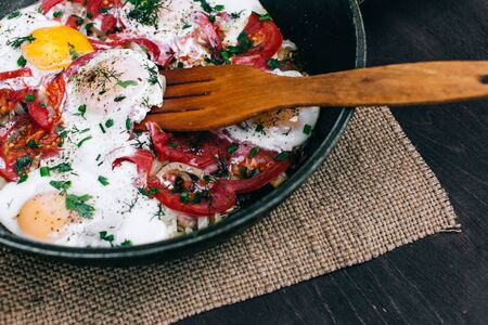 Cooking dinner. Cooking Fried eggs with tomatoes and onions in a panの写真素材