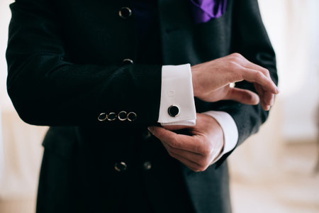A man in a business suit fastens a button on his sleeve.  Business concept.
