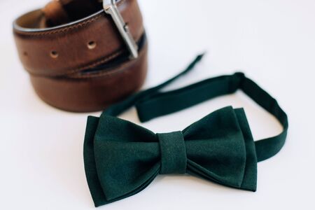 Menswear set. Men's accessories. Green bow tie and leather belt on a white background. Wedding morningの写真素材