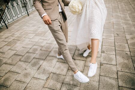 Bride and groom on the street  show their shoes.  Not classic wedding shoesの写真素材
