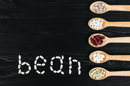 A colorful of beans in wood spoon on wood background