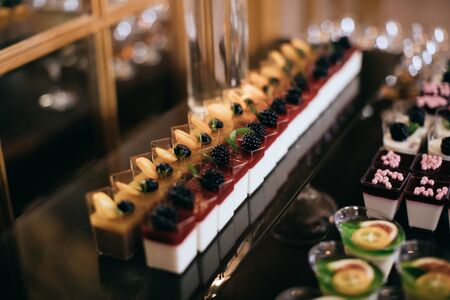 Delicious cakes with fresh berries on dessert table at wedding partyの写真素材
