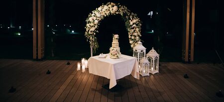 beautiful wedding cake with candles and flowers outdoorsの写真素材
