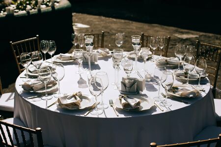 Outdoor catering. Elegant wedding table setting  with wine glasses and cutlery and decor with fresh flowers and candles  in the parkの写真素材