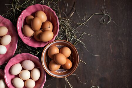 Preparing for Easter. Chicken eggs in colorful plates on a wooden tableの写真素材