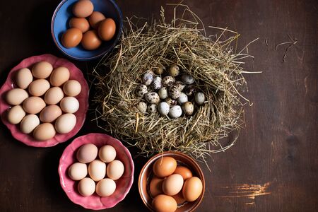 Preparing for Easter. Quail and chicken eggs on a wooden table in the kitchenの写真素材