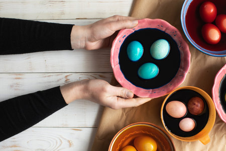 Preparation for Easter. Woman holding bowl with blue paints and easter eggs