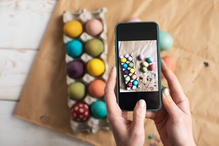 Woman making picture on mobile phone of painting Easter eggsの写真素材