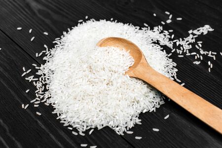 White rice in wooden spoon on dark backgroundの写真素材