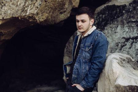 Portrait of a handsome young man in a denim jacket outdoors