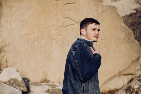Young man leaning against rock wall