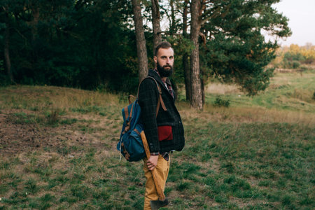 Bearded man with a backpack standing in the forest. Travel concept