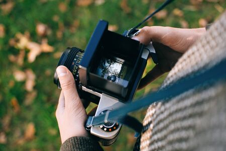 man photographer is making landscape photography with old film camera	の写真素材