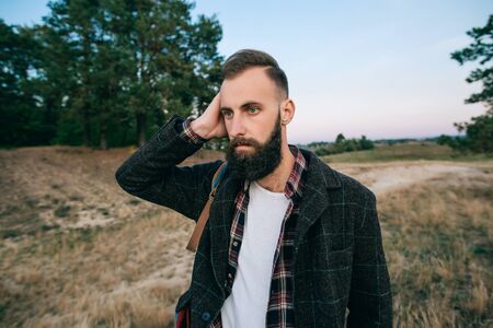 Young bearded hipster man holding hands behind headの写真素材