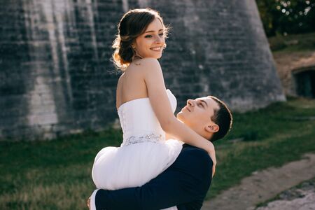 Bride and groom at wedding Day walking Outdoors on castle territory. Bridal couple, Newlywed woman and man embracing with love. People happy and smile. The bride to the groom's hands.の写真素材