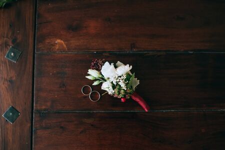 wedding rings bride and groom lying on a vintage wooden floor near the boutonniere of flowers	
の写真素材