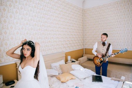 Groom portrait with a guitar in bedroom at a wedding day. Wedding morningの写真素材