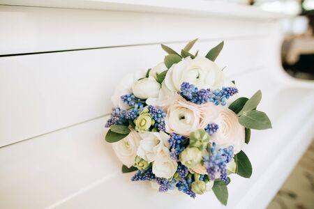Beautiful wedding bouquet with white and blue flowers lies on a white pianoの写真素材