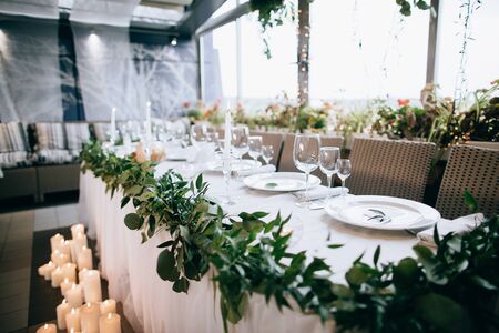 White plates, champagne glasses and wine and candles on wedding tableの写真素材