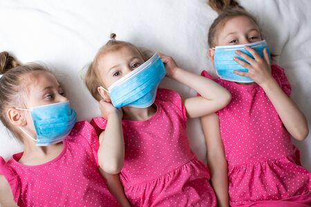 Funny Little children girls in medical masks. Global quarantine at home. Pandemic protectionの写真素材