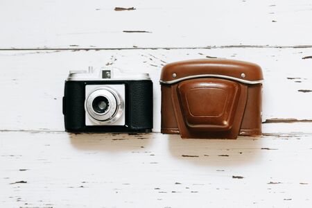 Old film camera in brown vintage case and a roll of film on wood background. top view, text spaceの写真素材