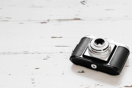 Old Retro photo camera on a white wooden desk. Vintage background. text space
