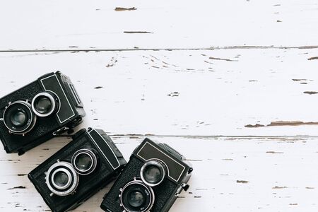 collection old vintage retro photo cameras on white wooden background. top view, medium format	の写真素材