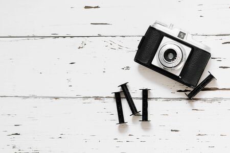 Retro camera, old photo film rolls on white wooden background. top view, text spaceの写真素材
