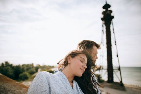 Young couple hugging and dreaming on the background of an old lighthouseの写真素材