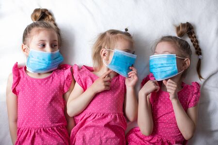 Three little girls in protective medical masks. Protection against viruses and coronavirusの写真素材