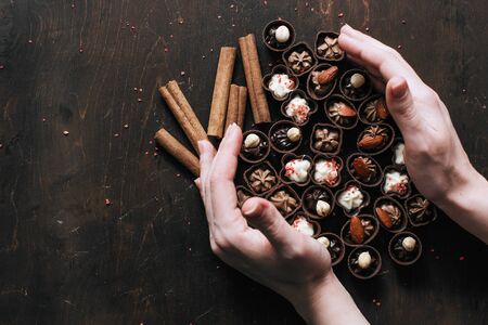 woman holding a lot of delicious chocolates. Sweets at homeの写真素材