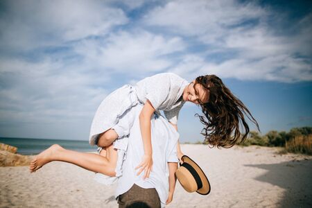 Guy carrying a girl on his back, at the beach, outdoors. Love conceptの写真素材