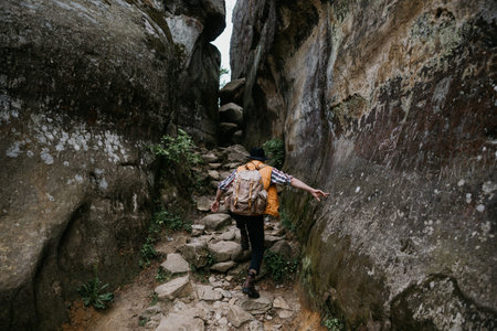 Hiker man in mountains. tourist with a backpack climbs a rock