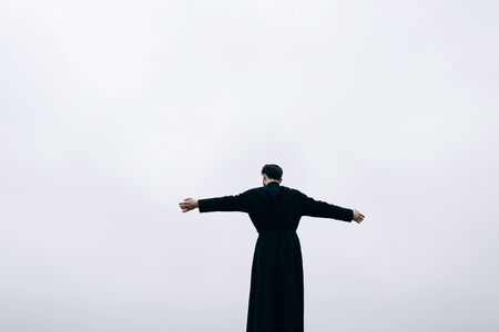 Priest bearded man raised his hands up on the hill above the town. Pastor posing outdoors in mountainsの写真素材