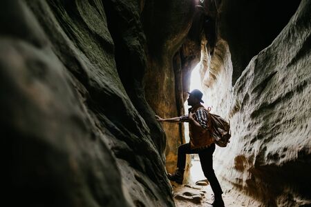 The traveler stands in a mountain cave. Hiking in the mountainsの写真素材