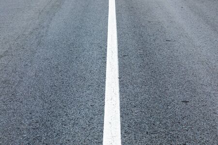 long lonely old asphalt road horizontal background with a white solid stripeの写真素材
